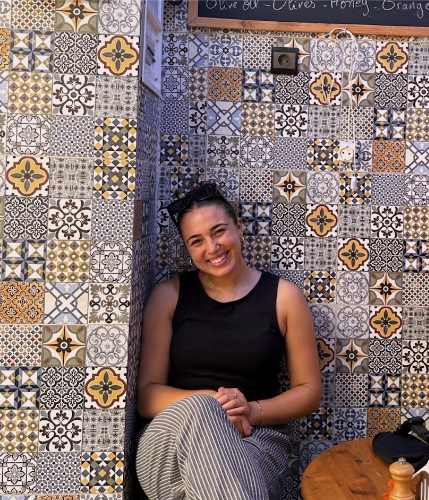 Student intern Grace Shawah sitting in front of a mosaic tiled wall