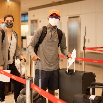 Students in line at airport with UVA hat and masks