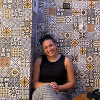 Student intern Grace Shawah sitting in front of a mosaic tiled wall
