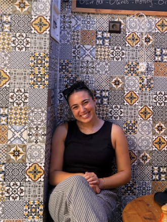 Student intern Grace Shawah sitting in front of a mosaic tiled wall