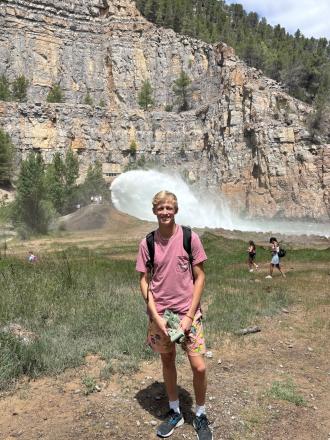 Intern Chris Rogers standing in a field with a mountain and water behind him